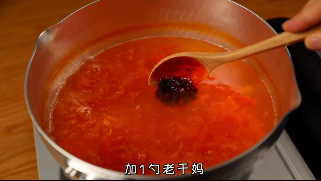 准备一颗番茄切块,然后倒入烧开的水,加入1匙「老干妈」辣酱。