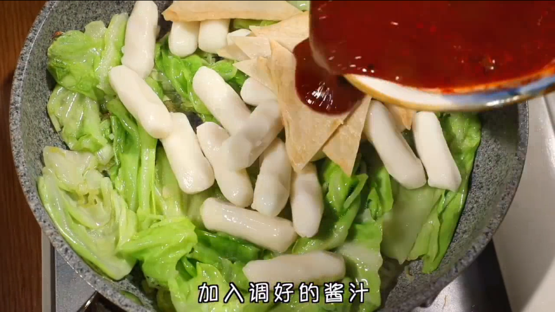 倒油热好的锅里加入大葱爆香,然后陆续加入包菜、韩式年糕和鱼饼,并倒入酱汁。炒匀后加入1碗水、加点泡菜,焖煮5分钟即可。