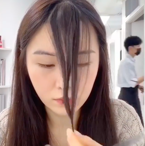 将之后把左右两撮头发拉往下巴处,将它们扭卷在一起后,再用剪刀打斜修剪掉部分发尾。