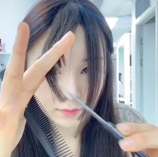 最后将一开始修剪的中间这撮发丝大略分到左右两侧,然后如是视频里的手法,打斜修剪掉修剪得不整齐的发丝即可。