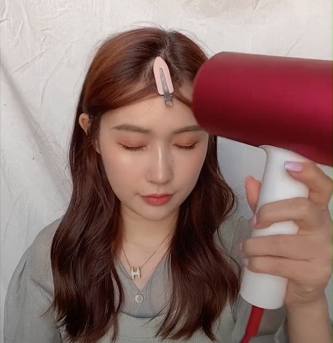 3、然后出动吹风筒，用有热度的风往刘海出吹5秒以上～