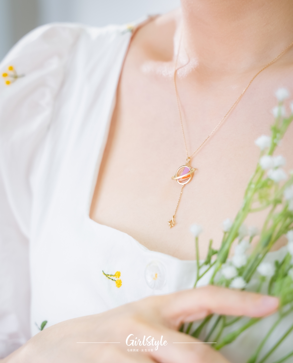 粉色及橙色琺琅细节为星球作点缀，仿佛染上了一层甜蜜气息满溢的浪漫粉色滤镜，与设计主调18K金碰撞出专属女生的青春活力感。吊坠每个细节都处理得精致感十足，满足细节控、星球元素控的所有幻想。