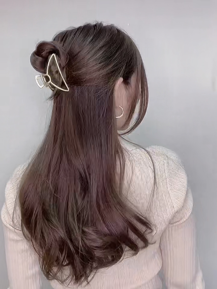 从头顶开始取出两侧上层的头发,再将两股头发编成麻花辫绕在一起,将头发向上绕成一个丸子。最后用一个中号的鲨鱼夹固定,把头顶和两侧的头发拨松,就完成元气满满的半丸子头造型啦!