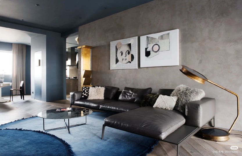 一进来客厅就能看到一整面灰雾气色的水泥墙面搭配金属材质,显得平静高雅,还挂了两幅很有艺术感的挂画。