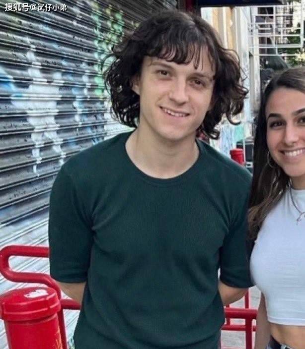 只见照片中的他整个人头发留长，还烫了一个卷发的造型。