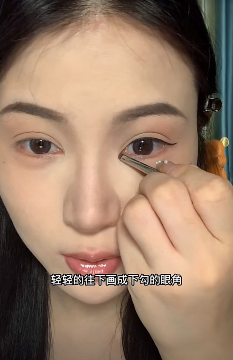 用深色眼影在眼头的部分往下画出眼角下勾的感觉