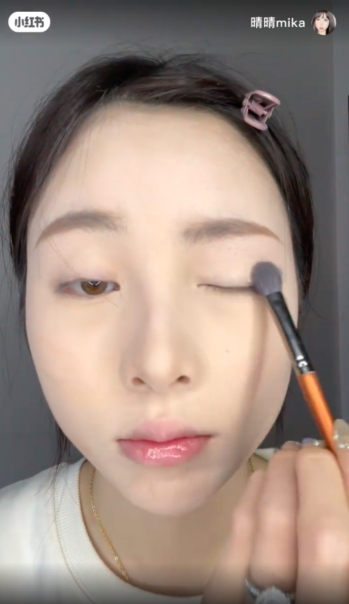 先选择一个较浅色的大地色系眼影,然后平铺涂抹在眼皮上。