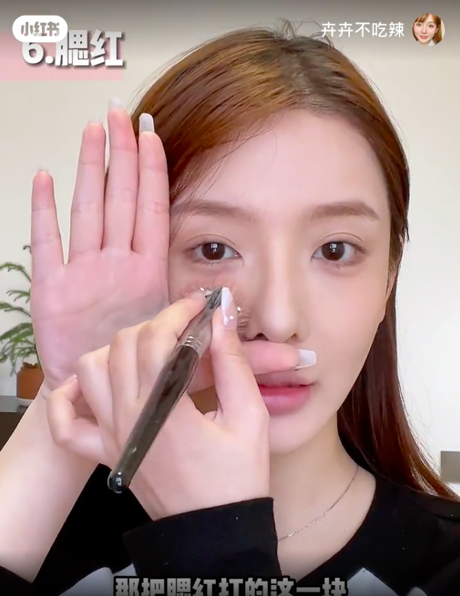 先用手比个“L”的手势卡在鼻子下面的位置，之后把腮红打在脸上